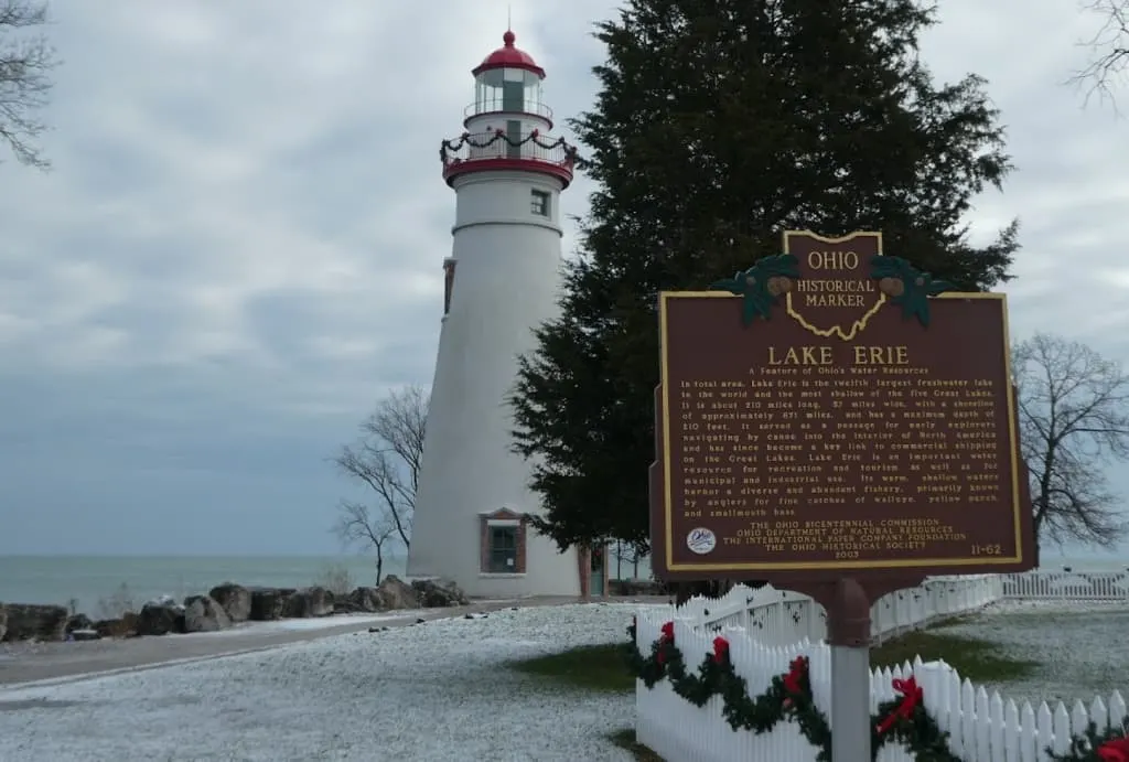Ohio historical marker with lighthouse and Lake Erie in background.