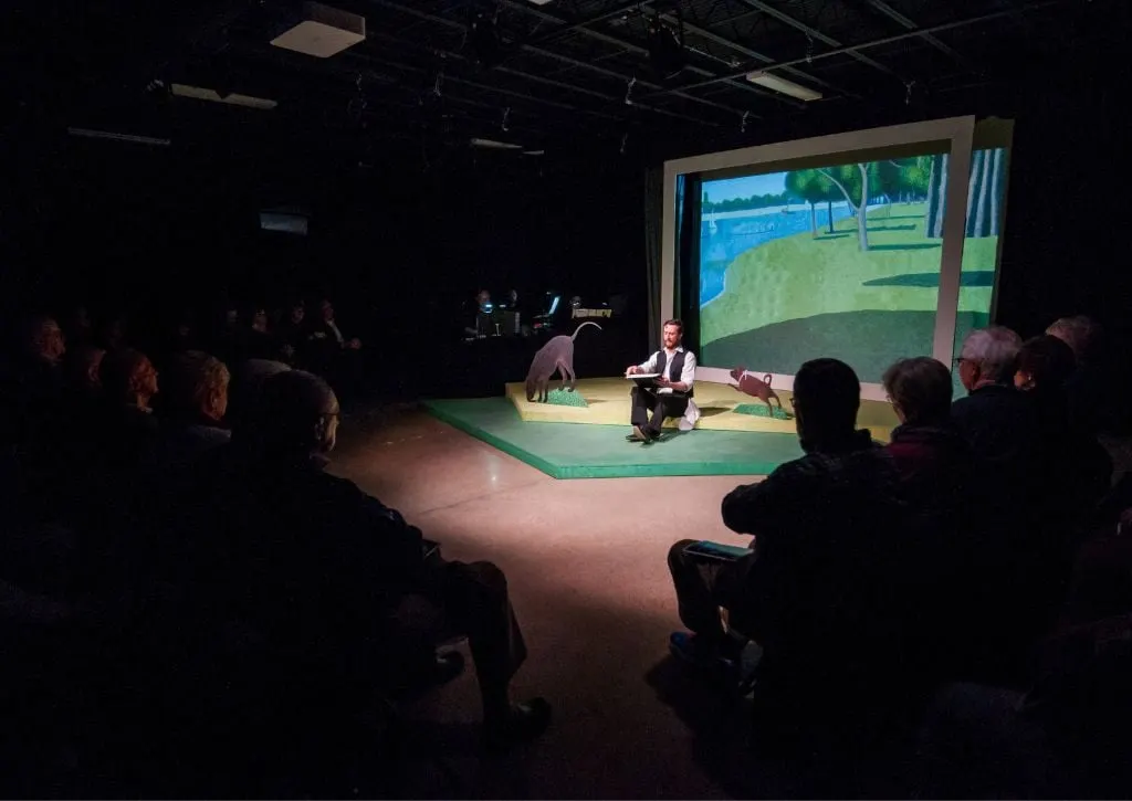 An audience gathers round to listen to a performer in a darkened room in Mansfield's Theatre 166. 
